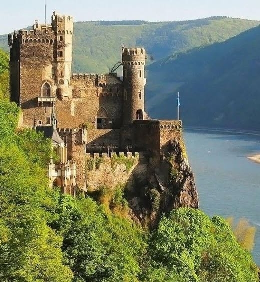Rheinstein Castle,  - located in the Upper Middle Rhine Valley in Germany. Built in the early 14th century, it served as a customs post for the Holy Roman Empire. Positioned atop a rocky cliff, it overlooks the Rhine River, offering breathtaking views and strategic significance.
Rheinstein Castle underwent restoration in the 19th century to preserve its medieval character and is now a popular tourist destination. Its Gothic architecture, stunning location, and historical charm make it a highlight of the Rhine Valley. Visitors can explore its well-preserved rooms, gardens, and enjoy the picturesque surroundings. It stands as a testament to the region’s rich cultural and architectural heritage.