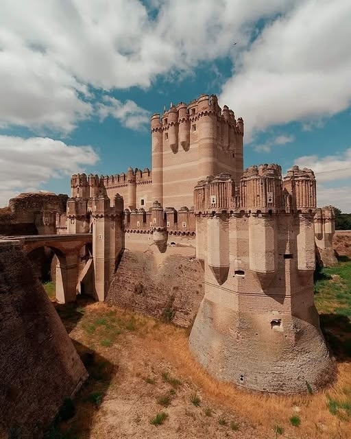 Das Schloss von Coca  - in Zentralspanien ist ein atemberaubendes architektonisches Meisterwerk aus dem 15. Jahrhundert. Diese Festung wurde von einem maurischen Architekten entworfen – eine übliche Praxis im Mittelalter – ist eine bemerkenswerte Mischung aus spanischem Mudejar-Mauerwerk und gotischen Elementen. Seine komplizierten Ziegelmuster, geometrische Entwürfe und ornamentale Details zeigen die einzigartige Verschmelzung islamischer und christlicher künstlerischer Traditionen, die den kulturellen Austausch der Zeit widerspiegel
Die Burg ist für ihre Verteidigungsmerkmale bekannt und verfügt über einen tiefen Burggraben, robuste Mauern und strategisch platzierte Türme, allesamt mit Präzision und Kunstfertigkeit. Der Mudejar-Stil, der sich durch die Verwendung von Ziegel- und dekorativen Motiven auszeichnet, zeigt sich im ganzen Bauwerk deutlich, während gotische Einflüsse in seinen spitzen Bögen und Gewölbedecken zu sehen sind.
Heute wird das Coca-Schloss als eines der besten Beispiele für mittelalterliche Architektur Spaniens gefeiert. Es dient als Beweis für das Können und die Kreativität seiner Bauherren und bietet den Besuchern einen Einblick in die reiche Geschichte und das kulturelle Erbe der Region. Ob Sie Architektur-Enthusiast oder Geschichtsfan sind, dieses Schloss ist ein unbedingt gesehenes Ziel, das das künstlerische und historische Erbe des mittelalterlichen Spaniens wunderschön einkapselt.